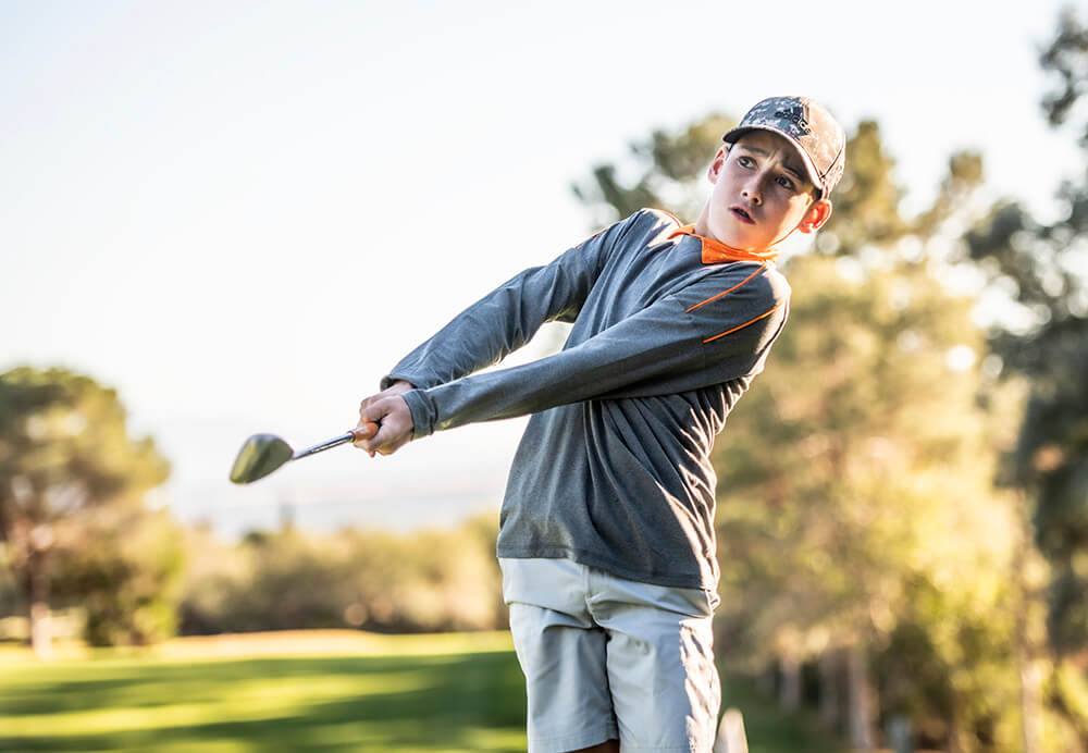 Young golfer swinging club