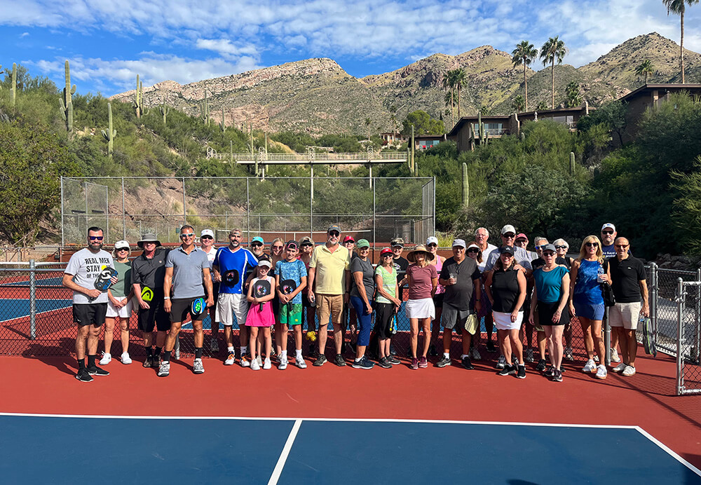 large group of pickleball players posing for picture on court